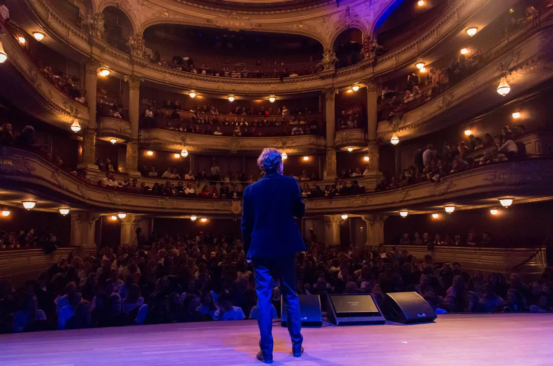 A host on stage facing a full theatre